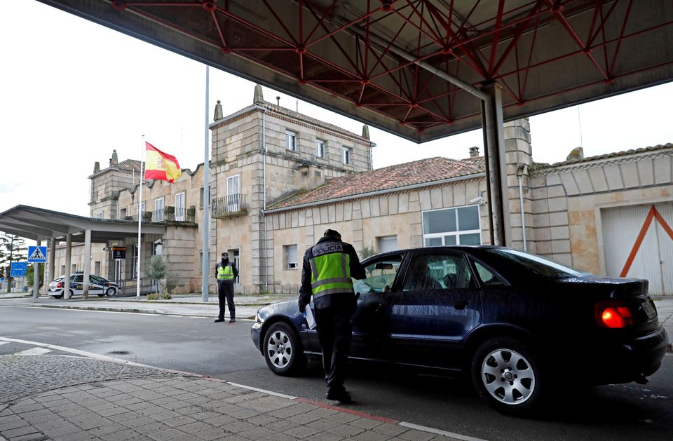 FILE PHOTO/A Spanish police officer checks a car at the border between Portugal and Spain,REUTERS