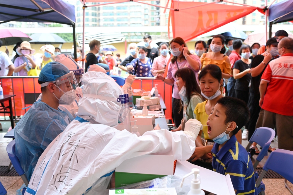A medical worker collects a swab from a resident during a mass testing for the coronavirus disease (COVID-19) at a makeshift testing site at a stadium in Guangzhou, Guangdong province, China May 30, 2021. cnsphoto via REUTERS 