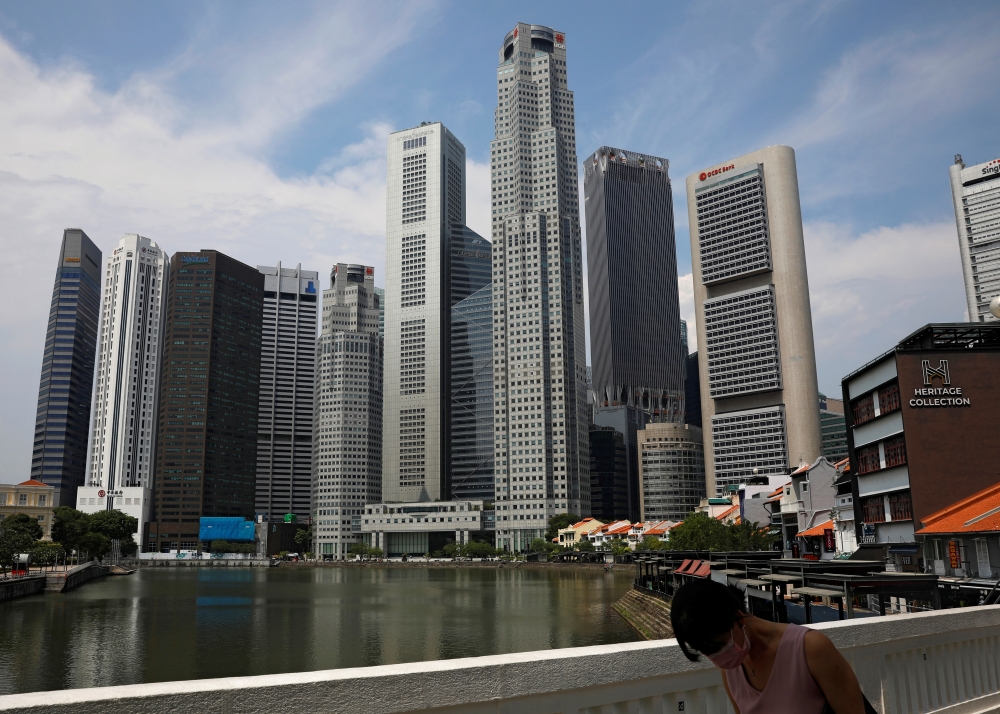 A woman wearing a protective face mask passes the city skyline during the coronavirus outbreak (COVID-19) outbreak in Singapore June 10, 2021. REUTERS/Edgar Su