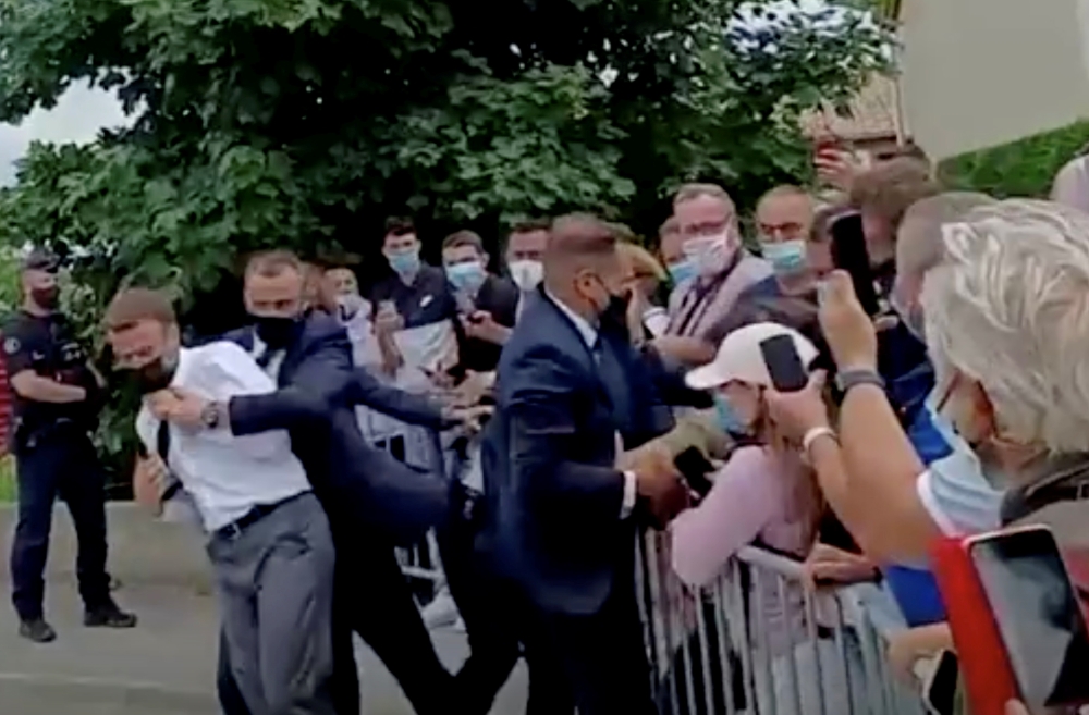 French President Emmanuel Macron is protected by a security member after getting slapped by a member of the public during a visit in Tain-L'Hermitage, France, in this still image taken from video on June 8, 2021. (BFMTV/ReutersTV)
