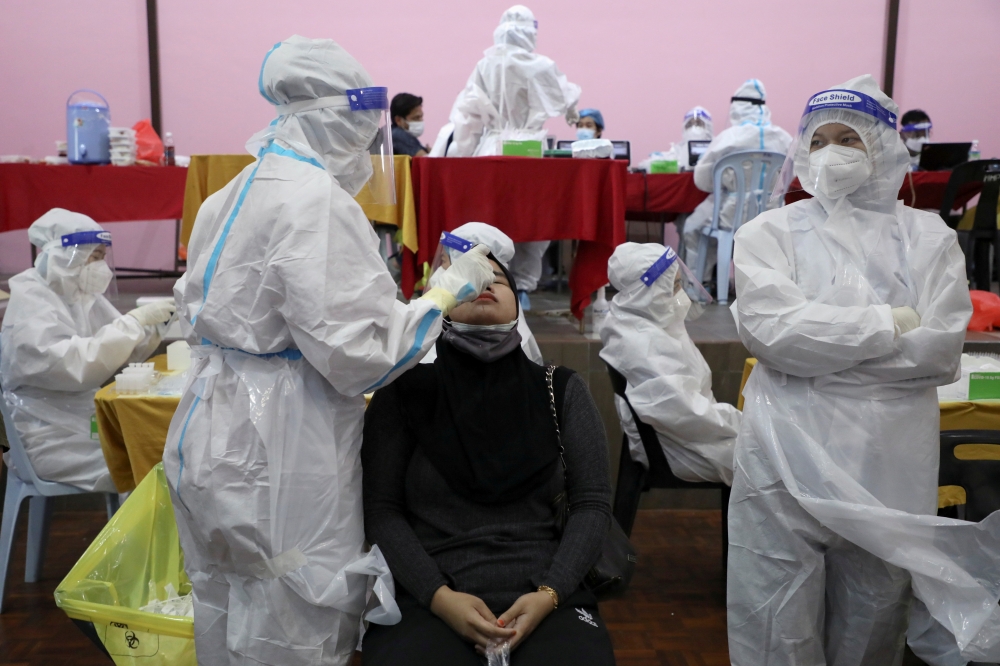A medical worker collects a swab sample from a woman to be tested for the coronavirus disease (COVID-19) in Cyberjaya, Malaysia, June 2, 2021. REUTERS/Lim Huey Teng/File Photo