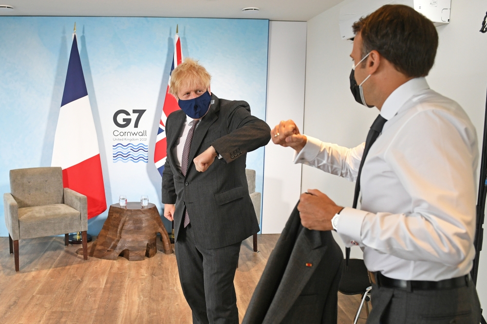 Britain's Prime Minister Boris Johnson and France's President Emmanuel Macron elbow bump as they attend a bilateral meeting during G7 summit in Carbis Bay, Cornwall, Britain, June 12, 2021. (REUTERS)