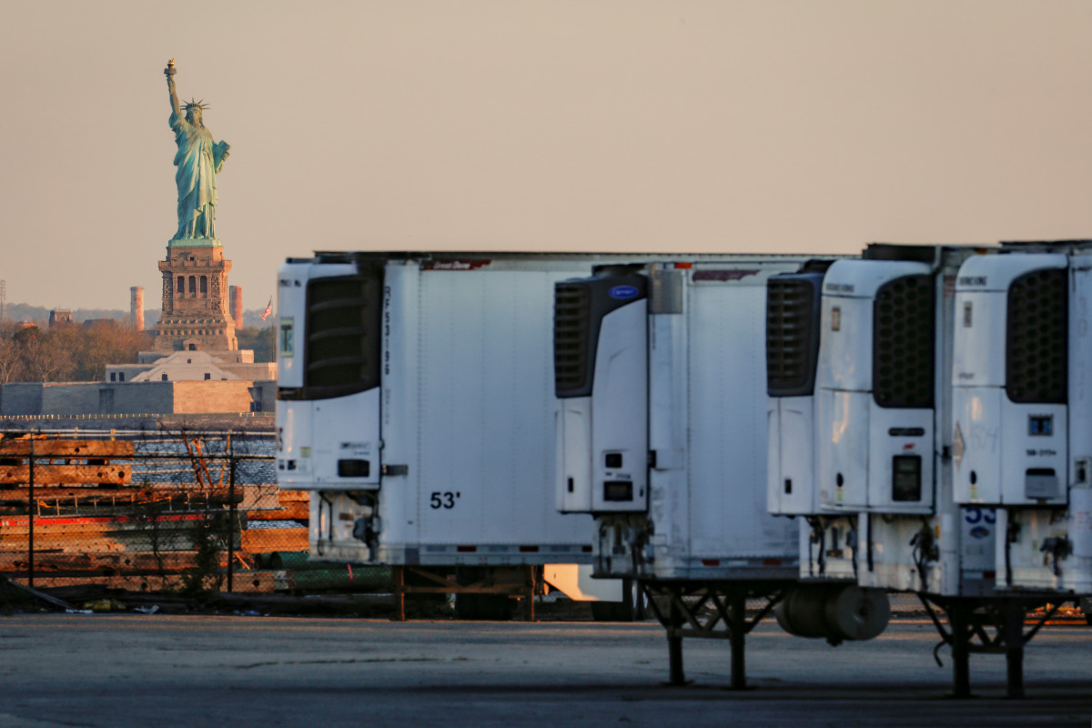 FILE PHOTO: Refrigerated tractor trailers used to store bodies of deceased people are seen at a temporary morgue, with the Statue of Liberty seen in the background, during the coronavirus disease (COVID-19) outbreak, in the Brooklyn borough of New York Ci