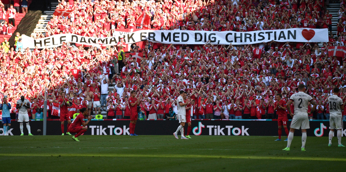 Soccer Football - Euro 2020 - Group B - Denmark v Belgium - Parken Stadium, Copenhagen, Denmark - June 17, 2021 Players and fans react after kicking the ball out in the 10th minute of the match to applaud Denmark's Christian Eriksen who remains in hospita