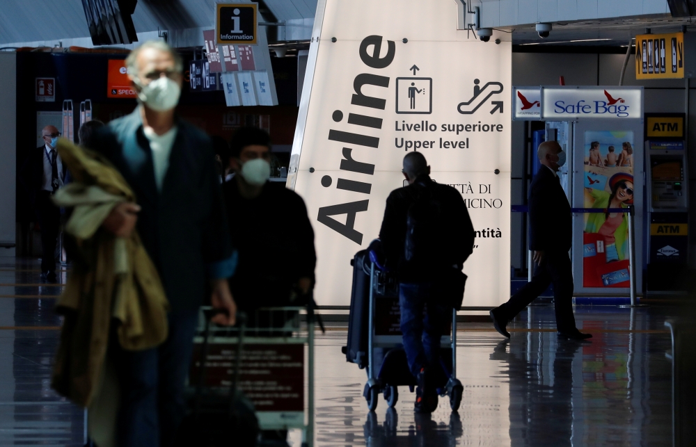 Travellers walk with their luggage at Fiumicino Airport... Reuters/Remo Casilli/File Photo