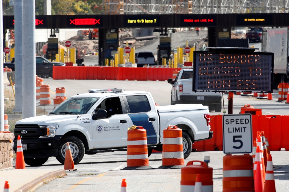 A US Customs and Protection vehicle stands beside a sign reading that the border is closed to non-essential traffic at the Canada-United States border crossing at the Thousand Islands Bridge, to combat the spread of the coronavirus disease (COVID-19) in L