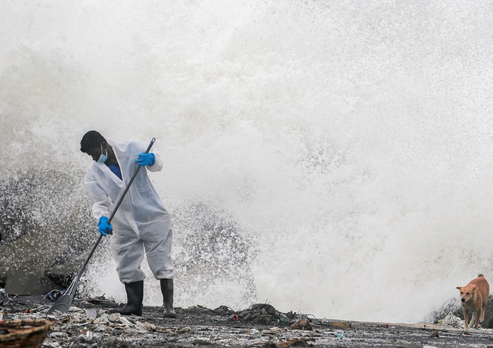 Sea water splashes behind a Sri Lankan navy member as he cleans the debris washed to a beach from the MV X-Press Pearl container ship, which caught fire and sank off the Colombo Harbour, in Ja-Ela, Sri Lanka June 14, 2021. REUTERS/Dinuka Liyanawatte