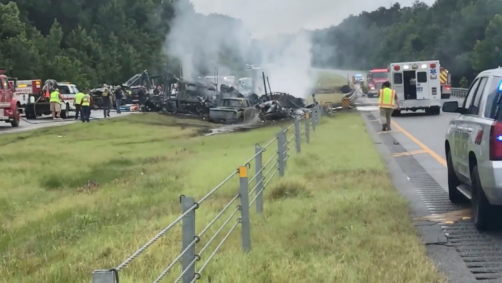 Emergency personnel work at the accident site as smoke rises from the wreckage after about 18 vehicles slammed together on a rain-drenched Alabama highway during Tropical Storm Claudette, in Butler County, Alabama, U.S., June 19, 2021, in this still image