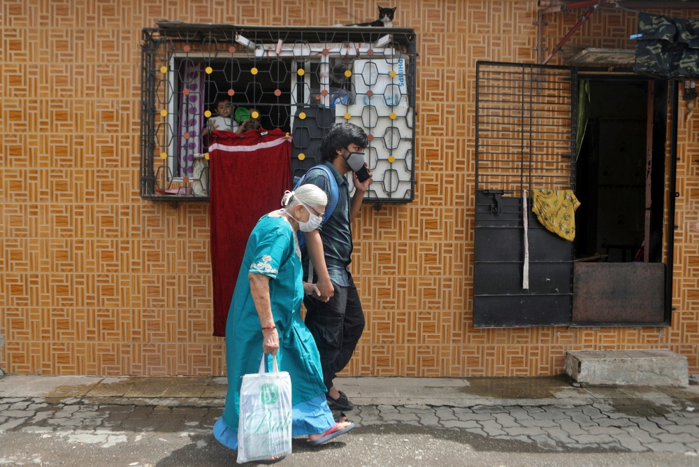 Madhura Samel, 81, walks with Om Rajesh Yadav, a volunteer from Robin Hood Army, a volunteer-based organisation, to board a taxi to reach to a coronavirus disease (COVID-19) vaccination centre in Mumbai, India, June 21, 2021. Picture taken on June 21, 202