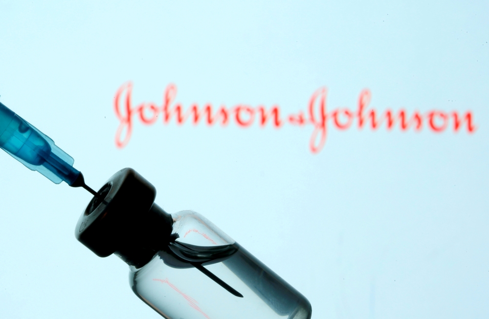 A vial and syringe are seen in front of a displayed Johnson & Johnson logo in this illustration taken January 11, 2021. REUTERS/Dado Ruvic/Illustration/File Photo