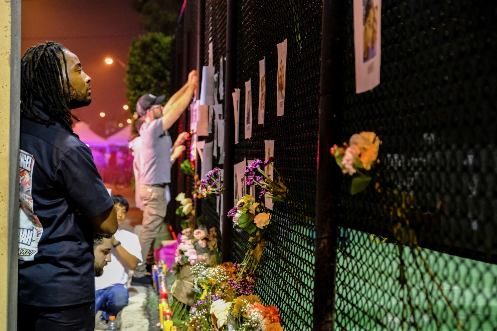 People hang up more signs of missing residents and light candles from the partial collapse in Surfside where the rescue personnel continue their search for victims the day after in Surfside near Miami Beach, Florida, U.S., June 25, 2021. (Reuters/Maria Al