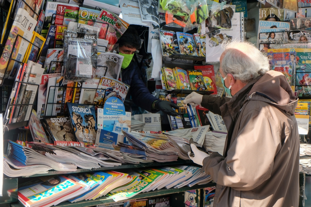 A man wears a protective face mask and gloves at the newsstand in Venice, Italy. (REUTERS/Manuel Silvestri/File Photo)