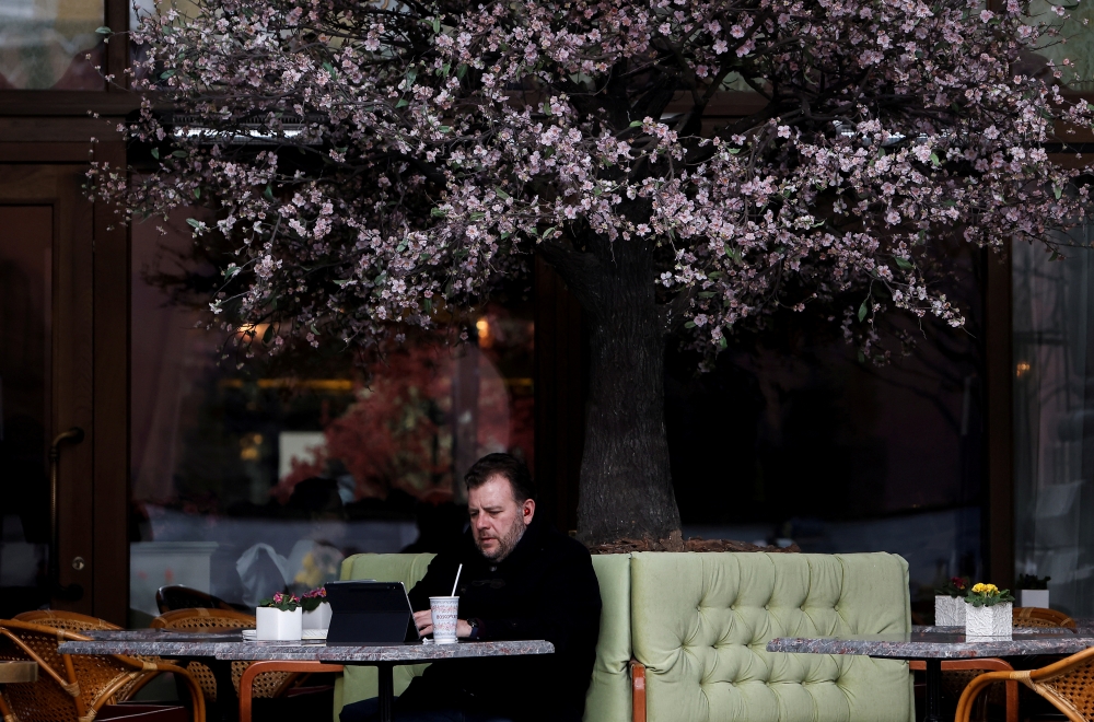 A man uses a tablet as he sits on a terrace at a cafe in Moscow, Russia March 23, 2021. REUTERS/Maxim Shemetov/File Photo