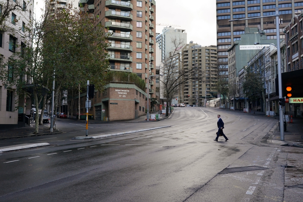 A pedestrian crosses an empty intersection at morning commute hour in the city centre during a lockdown to curb the spread of a coronavirus disease (COVID-19) outbreak in Sydney, Australia, June 28, 2021. REUTERS/Loren Elliott