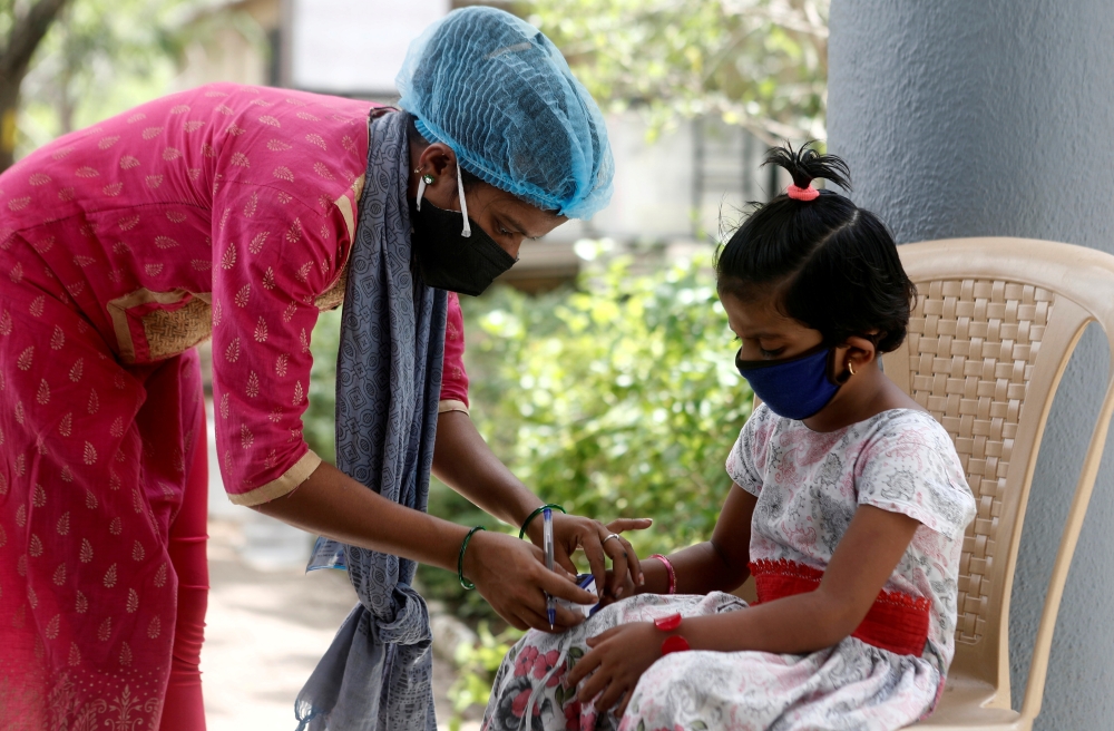 A nurse checks a coronavirus disease patient's pulse before she is admitted into a school turned COVID-19 care facility on the outskirts of Mumbai, India, May 24, 2021. REUTERS/Francis Mascarenhas/File Photo