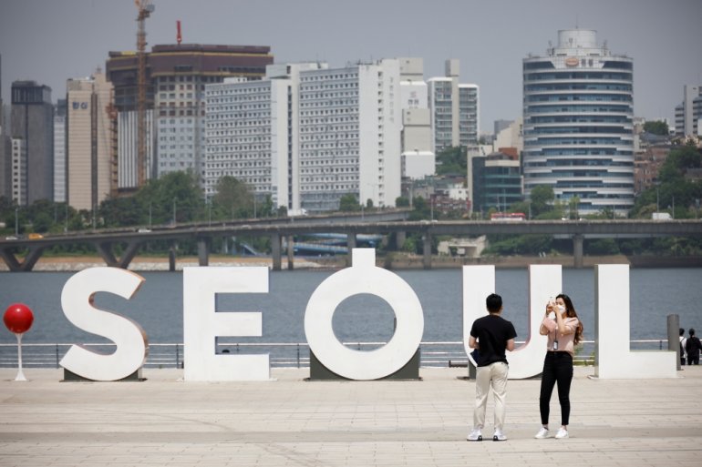 A woman wearing a mask amid the coronavirus disease (COVID-19) pandemic takes photographs of her boyfriend at a Han river park in Seoul, South Korea, May 24, 2021. Reuters/Kim Hong-Ji/File Photo