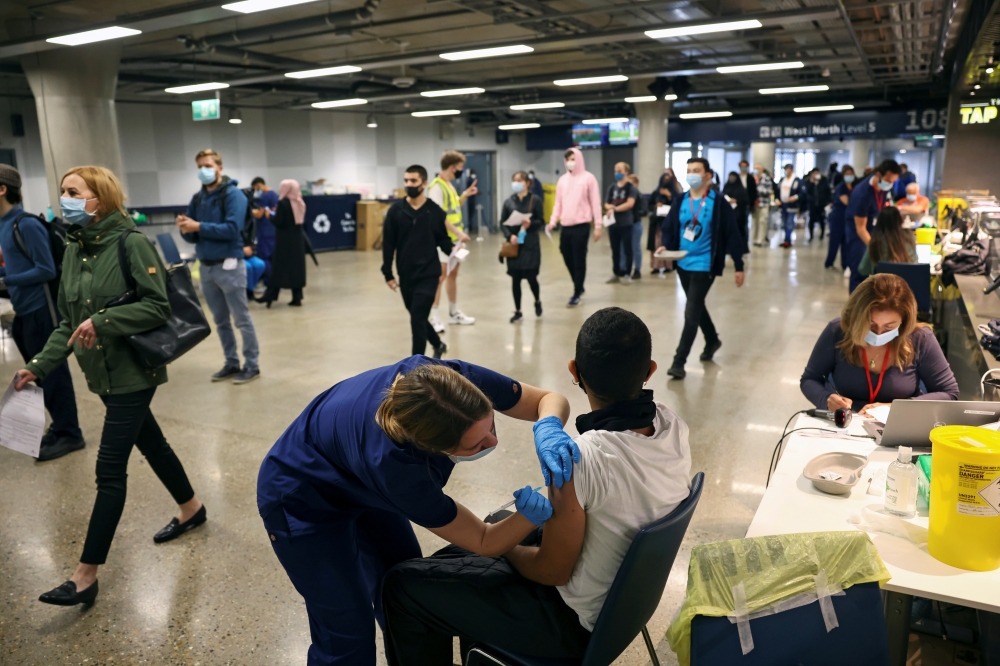 FILE PHOTO: A person receives a dose of the Pfizer BioNTech COVID-19 vaccine at a mass vaccination centre for those aged 18 and over at the Tottenham Hotspur Stadium, amid the coronavirus disease (COVID-19) pandemic, in London, Britain, June 20, 2021. REU