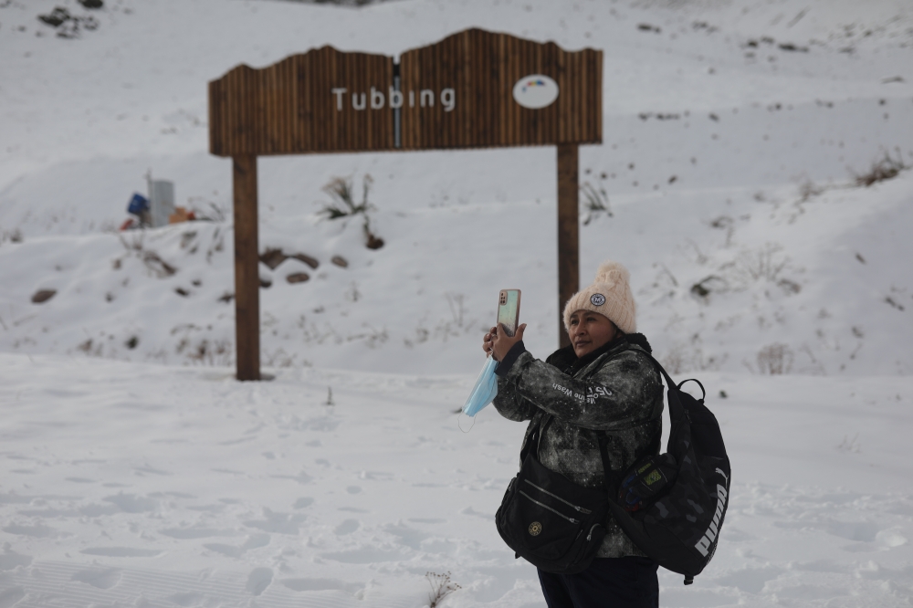 A tourist takes a photo at a mountain resort as Chile's health authority lifts closure restrictions at Farellones Park in Santiago, Chile, July 1, 2021. REUTERS/Pablo Sanhueza