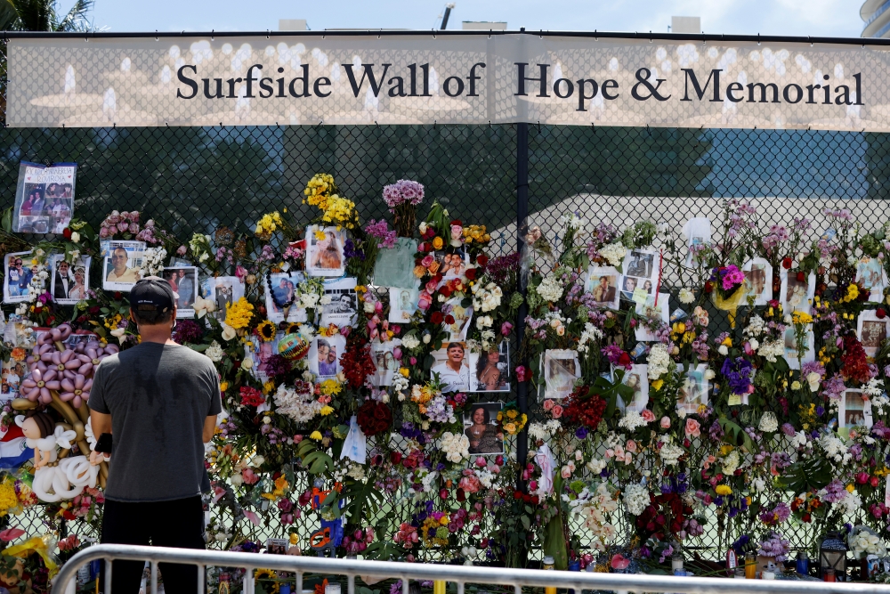 A man mourns at the memorial for victims of a partially collapsed residential building as the emergency crews continue the search and rescue operations for survivors, in Surfside, near Miami Beach, Florida, U.S. July 2, 2021. REUTERS/Marco Bello