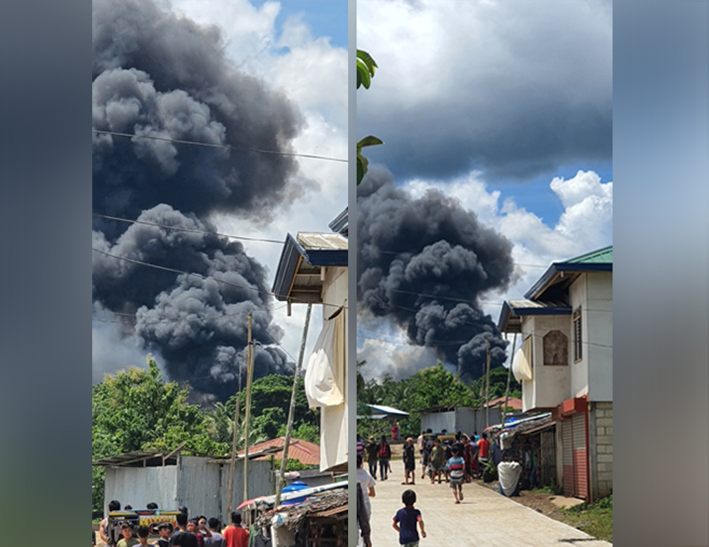 Residents gather as smoke rises from the wreckage, after a Philippines Air Force Lockheed C-130 transport plane, carrying troops, crashed on landing in Jolo, Sulu, Philippines July 4, 2021 in this image obtained from social media. Bogs Muhajiran via REUTE