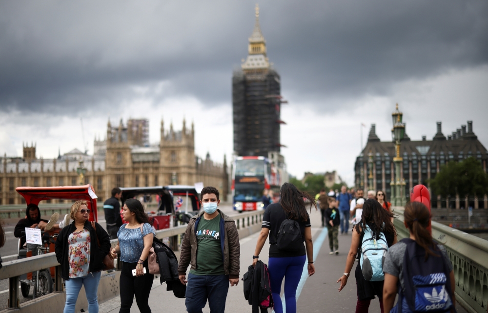 People, some wearing protective face masks, walk over Westminster Bridge, amid the coronavirus disease (COVID-19) pandemic, in London, Britain, July 4, 2021. REUTERS/Henry Nicholls/File Photo