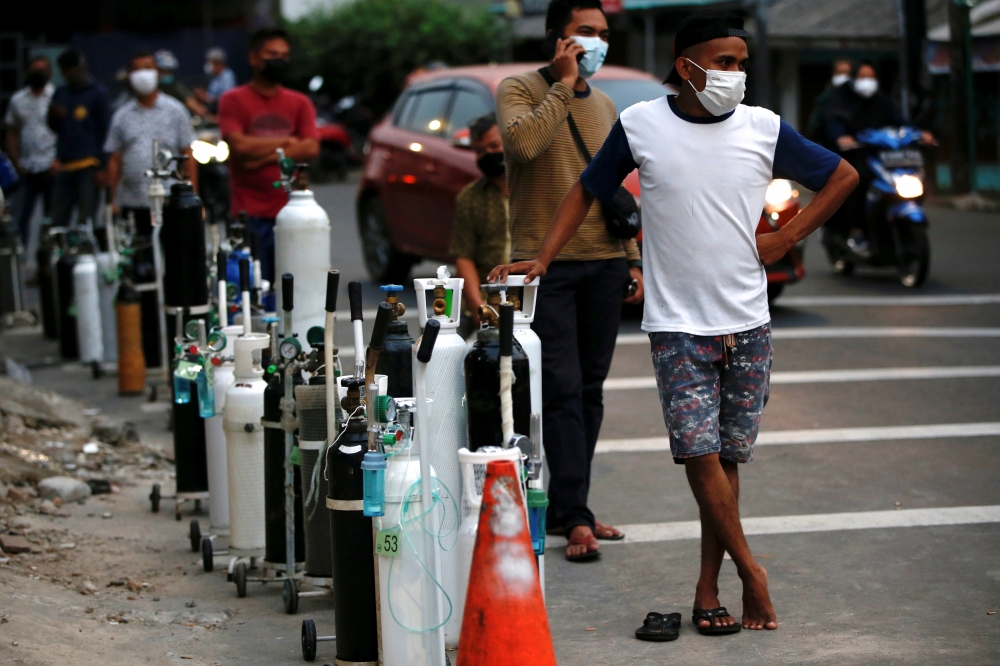 People wearing protective masks queue to refill oxygen tanks as Indonesia experiences an oxygen supply shortage amid a surge of coronavirus disease (COVID-19) cases, at a filling station in Jakarta, Indonesia, July 5, 2021. REUTERS/Willy Kurniawan/File Ph