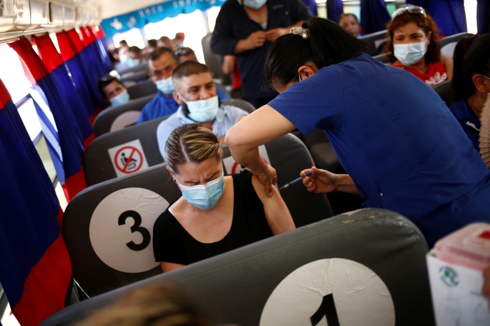 Employees of an assembly factory receive a dose of the Pfizer-BioNTech coronavirus disease (COVID-19) vaccine aboard a bus during a mass vaccination program for people over 40 years of age at a university in Ciudad Juarez, Mexico July 05, 2021. REUTERS/Jo