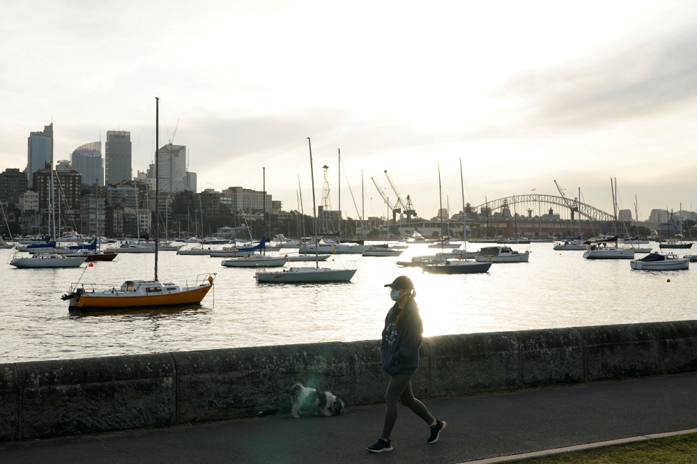 A woman wearing a protective face mask walks along a waterfront path during a lockdown to curb the spread of a coronavirus disease (COVID-19) outbreak in Sydney, Australia, July 8, 2021. REUTERS/Loren Elliott/File Photo/File Photo