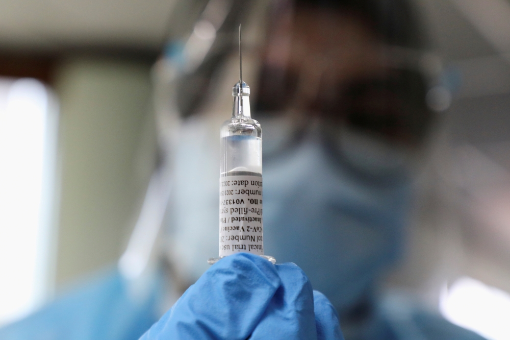 A medical worker holds a dose of Biokangtai's coronavirus disease (COVID-19) vaccine during a vaccination program at a factory, in Pulau Indah, Malaysia July 8, 2021. REUTERS/Lim Huey Teng/File Photo