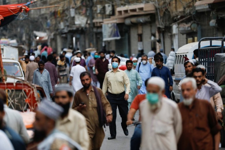 FILE PHOTO:A man wears a protective face mask as he walks among other people along a street, as the outbreak of the coronavirus disease (COVID-19) continues, in Karachi, Pakistan June 16, 2020. REUTERS/Akhtar Soomro
