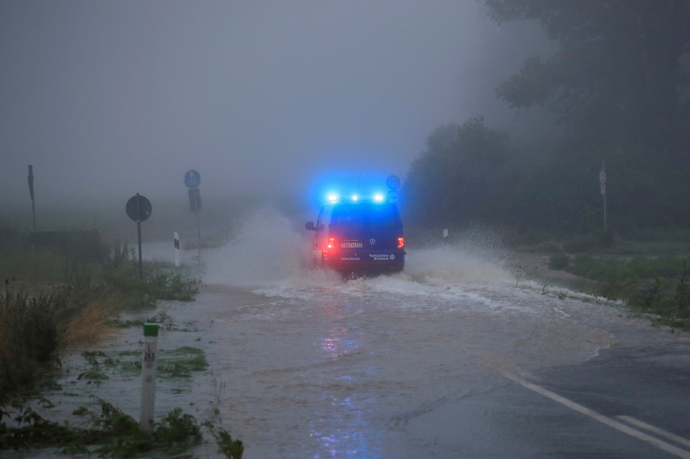 A vehicle travels on a flood-affected road after the Erft river swelled following heavy rainfalls in Erftstadt, near Cologne, Germany, July 15, 2021. REUTERS/Wolfgang Rattay