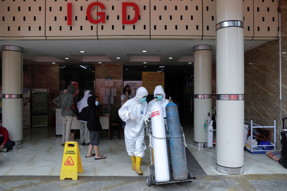 Medical workers in Personal Protective Equipment (PPE) push oxygen cylinders outside the emergency ward of a government-run hospital amid the surge of coronavirus disease (COVID-19) in Bekasi, on the outskirts of Jakarta, Indonesia, July 15, 2021. (REUTER