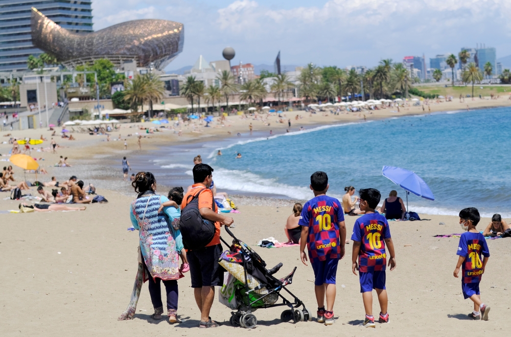 Children wear t-shirts of Barcelona soccer player Lionel Messi next to their parents at Barceloneta beach in Barcelona, Spain, July 14, 2021. REUTERS/Nacho Doce/File Photo