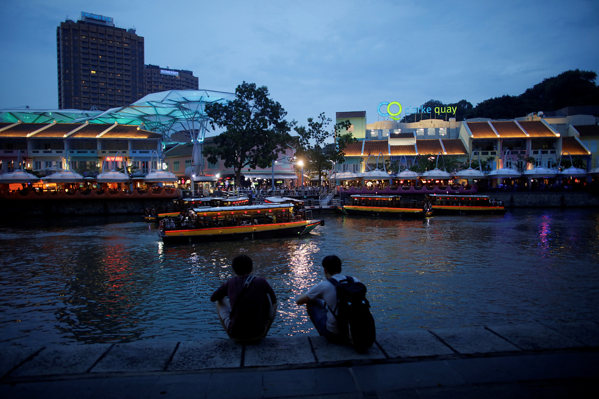 FILE PHOTO: People sit on the banks of the Singapore River at Clarke Quay in Singapore April 14, 2018. REUTERS/Thomas White/File Photo
