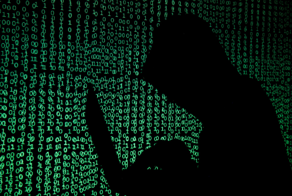 FILE PHOTO: A hooded man holds a laptop computer as cyber code is projected on him in this illustration picture taken on May 13, 2017.\. REUTERS/Kacper Pempel/Illustration/File Photo

