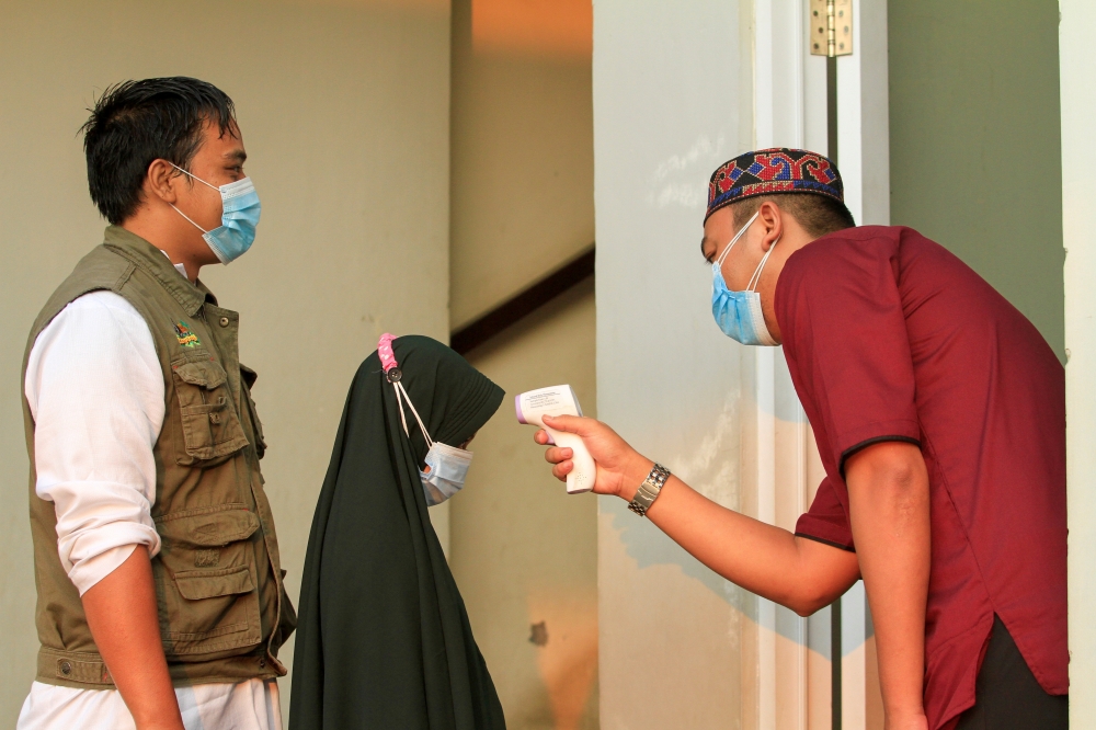 An Indonesian Muslim is checked with a thermal scanner before entering a mosque to offer Eid al-Adha prayers amid a surge of coronavirus disease (COVID-19) cases in Bogor, on the outskirts of Jakarta, Indonesia, July 20, 2021. REUTERS/Ajeng Dinar Ulfiana