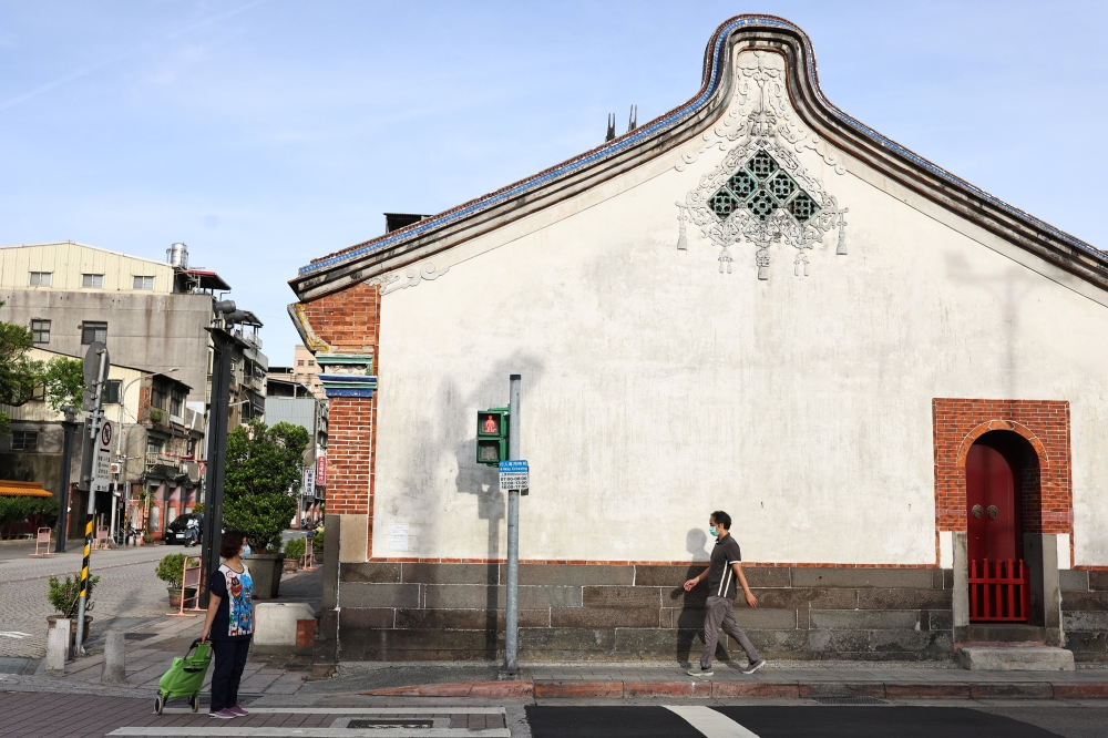 People wearing protective face mask walk past a temple amid the coronavirus disease (COVID-19) pandemic, in Taipei, Taiwan, July 16, 2021. REUTERS/Ann Wang