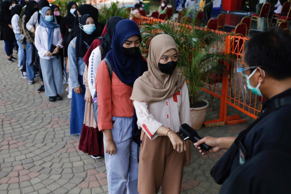 A girl has her temperature checked as she arrives to receive China's Sinovac Biotech vaccine against the coronavirus disease (COVID-19) during a mass vaccination program at Ancol amusement park in Jakarta, Indonesia, July 24, 2021. REUTERS/Willy Kurniawan