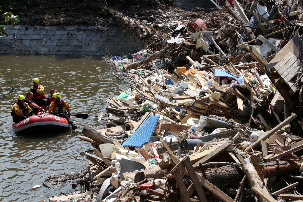 Rescuers and police officers with a dog look for victims in a flood, in Trooz, Belgium, July 20, 2021. REUTERS/Yves Herman 