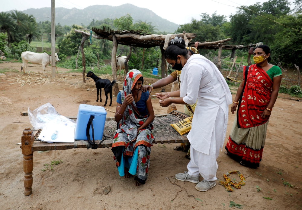 FILE PHOTO: Healthcare worker Jankhana Prajapati gives a dose of the domestically manufactured COVISHIELD vaccine to villager Amiyaben Dabhi during a door-to-door vaccination drive in Banaskantha district in the western state of Gujarat, India, July 23, 2