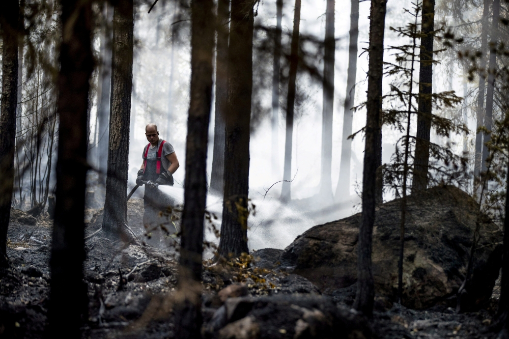 Fire departments and volunteers work to control a forest fire in Pyharanta, Western Finland July 19, 2018. Roni Lehti/Lehtikuva via Reuters