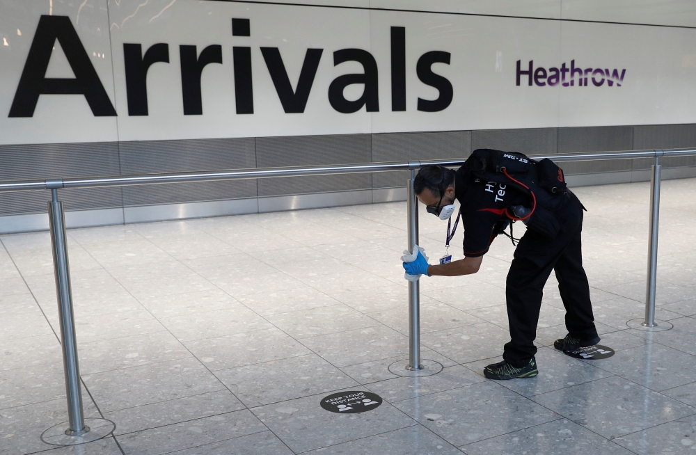 A worker sanitises a barrier at the International arrivals area of Terminal 5 in London's Heathrow Airport, Britain, August 2, 2021. REUTERS/Peter Nicholls