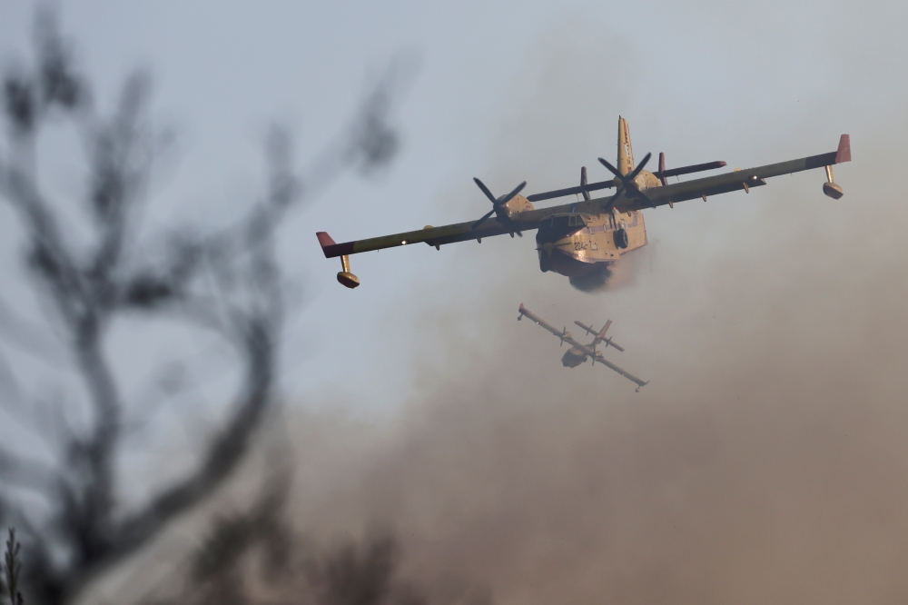 Firefighting airplanes fly as a wildfire continues to rage at Varympompi suburb north of Athens, Greece, August 4, 2021. REUTERS/Giorgos Moutafis