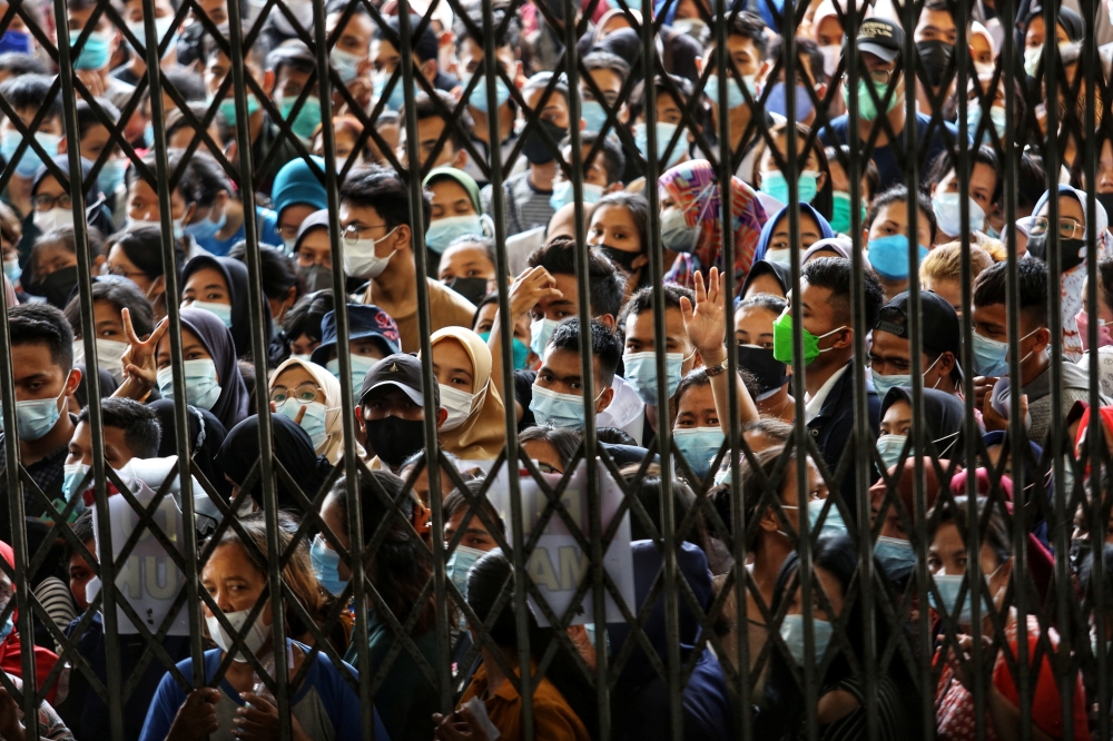 People wearing protective face masks stand in line wait to receiving a dose of the vaccine against the coronavirus disease (COVID-19), during a vaccination program at the provincial government building in Medan, North Sumatra province, Indonesia August 3,