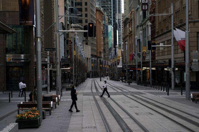 People in protective face masks walk through the quiet city centre during a lockdown to curb the spread of a coronavirus disease (COVID-19) outbreak in Sydney, Australia, July 28, 2021. REUTERS/Loren Elliott
