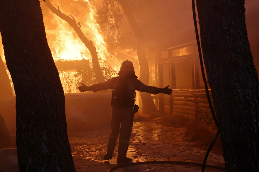 A firefighter reacts as a wildfire burns at Varympompi suburb north of Athens, Greece, August 3, 2021. REUTERS/Giorgos Moutafis/File Photo