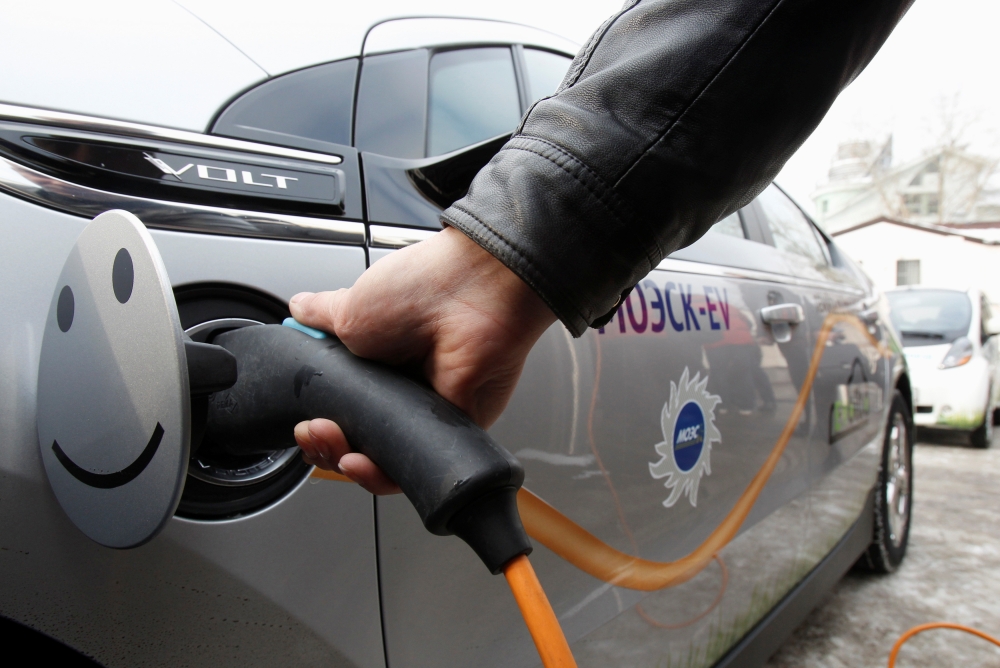 A man charges an electric car during a demonstration ceremony to launch a charging station, owned by the Moscow United Electric Grid Company (MOESK), in Moscow February 28, 2012. REUTERS/Sergei Karpukhin/File Photo
