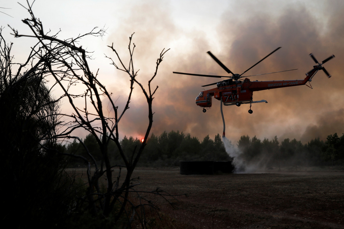 A helicopter is being filled up with water from a tank as a wildfire burns near the village of Kryoneri, north of Athens, Greece August 5, 2021. REUTERS/Costas Baltas
