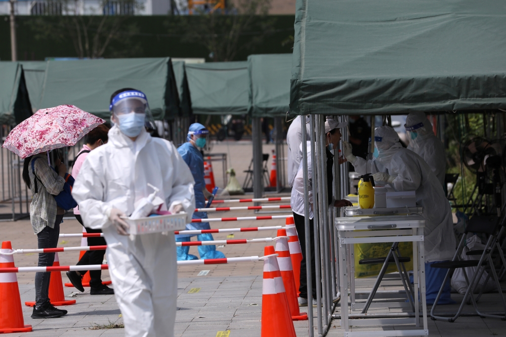 A medical worker collects a swab from a person at a nucleic acid testing site at a park, following new cases of the coronavirus disease (COVID-19), in Beijing, China August 6, 2021. REUTERS/Tingshu Wang