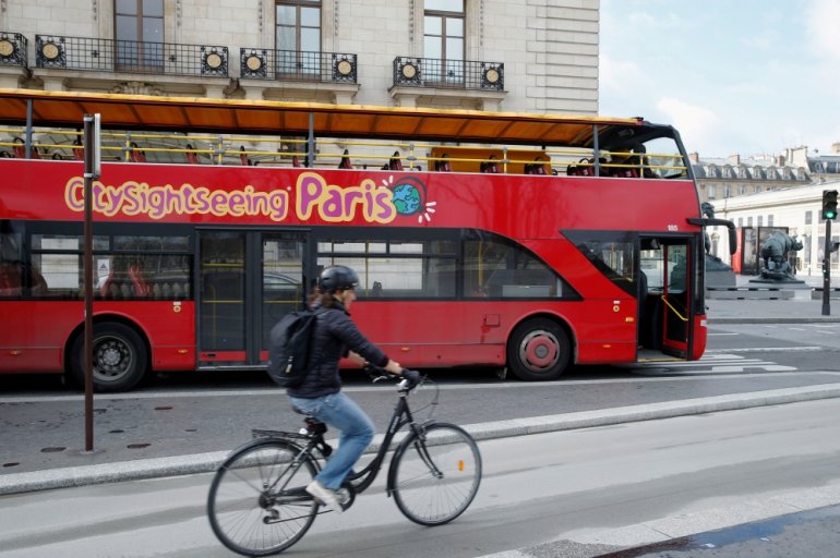 A cyclist rides past an empty tourist bus on the street of Paris, France, March 9, 2020. REUTERS/Pascal Rossignol/File Photo